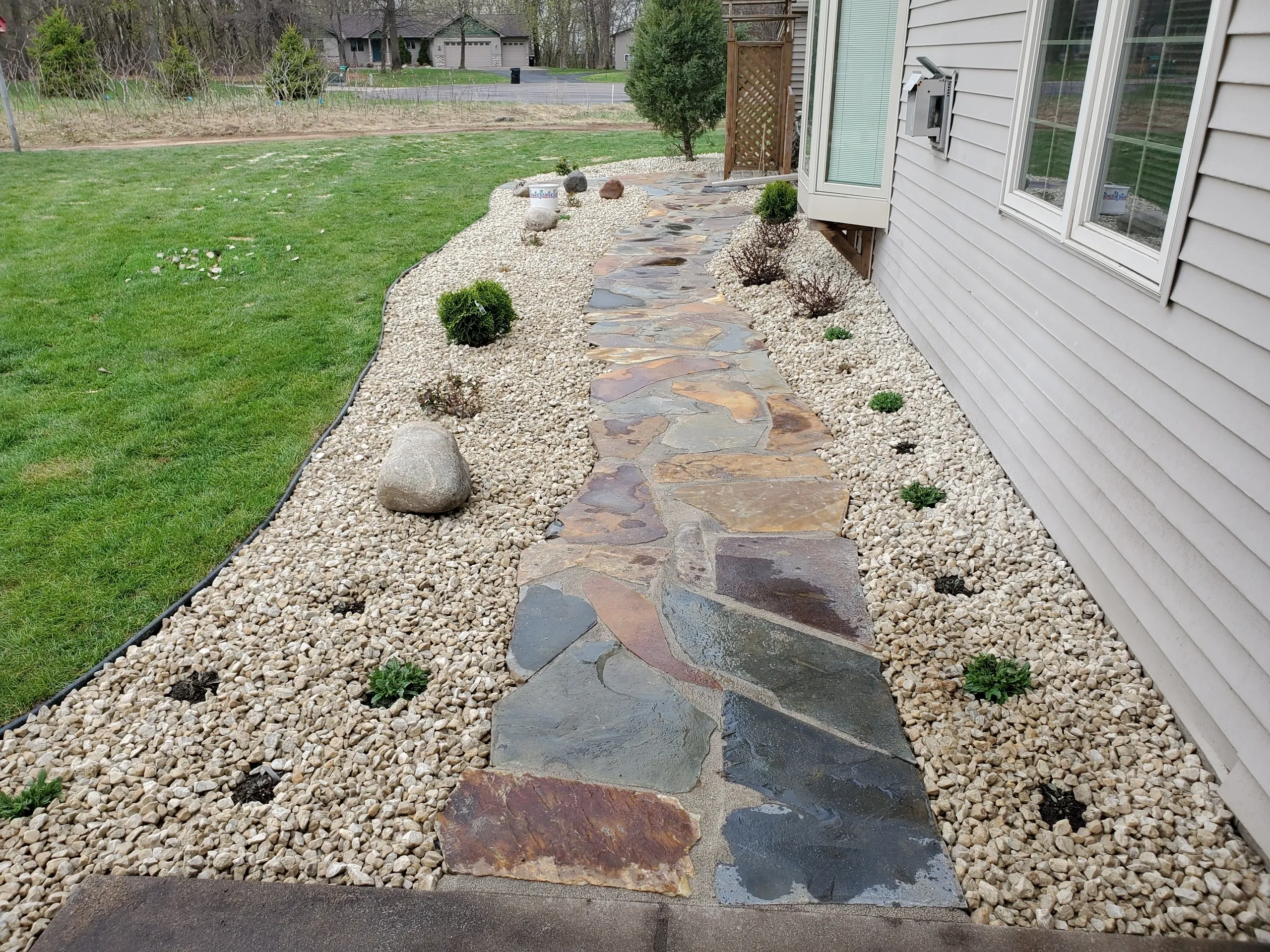 A walkway with stone steps and rocks in the yard.