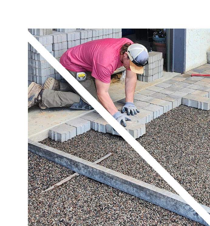 A man working on the ground of a brick walkway.